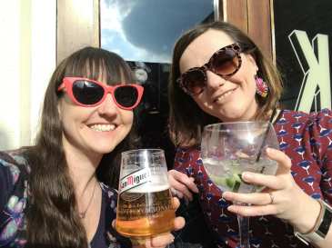me and my sister, wearing sunglasses, saying cheers with beverages.